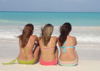 Three ladies sitting on a beach in beach clothes