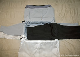 One pair of trousers layed over two shirts as third stage of bundle warpping packing