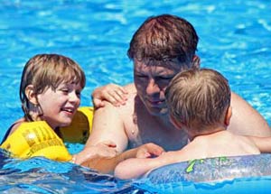 Kids playing with their father in a swimming pool