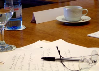 Glass of water, coffee cup and papers on a business meeting table