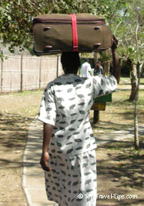 African woman carrying suitcase on her head