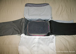 Packing cube layed over trousers and shirts as fifth stage of bundle wrapping packing