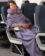 Woman sitting on airplane with travel blanket wrapped around her