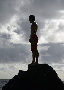 Man in swimsuits standing on a beach rock